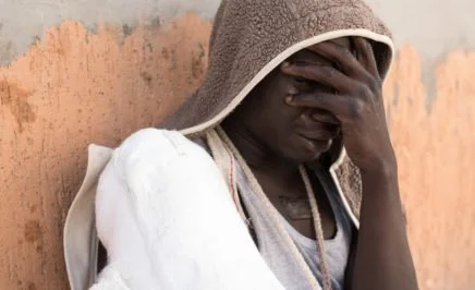 A refugee with his face in his hands.