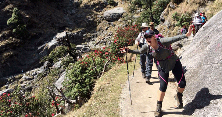 several people walking a trail on the side of a hill and looking at the camera