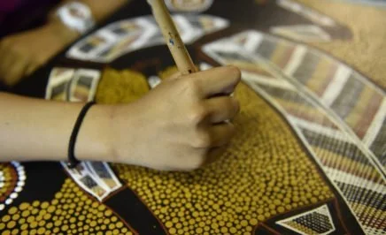 A girl making Aboriginal artwork