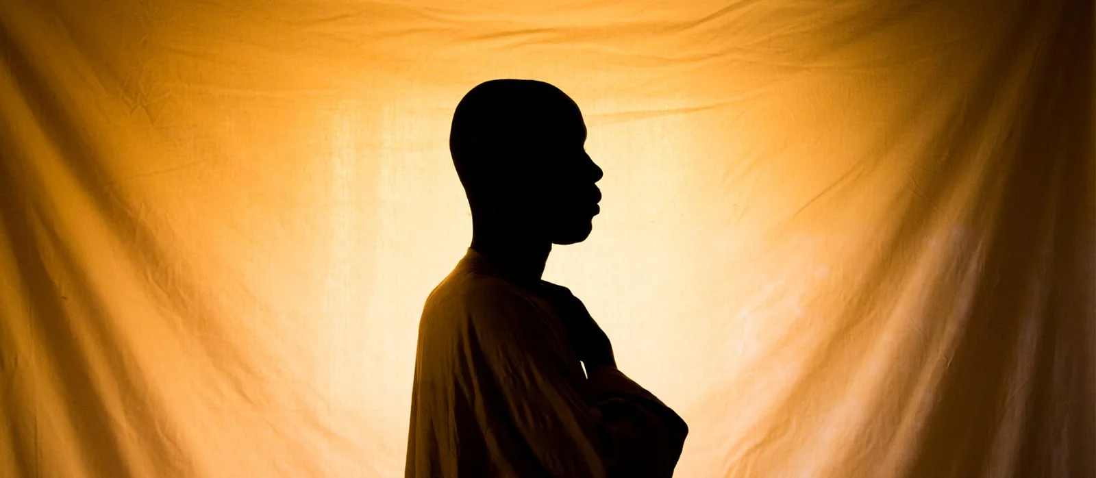 Silhouette of a man in front of an orange sheet