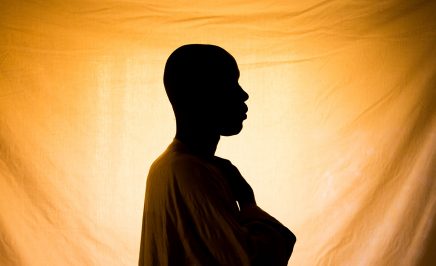 Silhouette of a man in front of an orange sheet