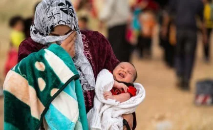 A young mother and refugee carries her baby in search of a safe home