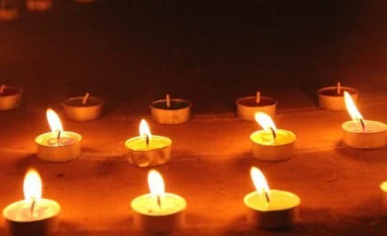 Close-up of some small lit candles lined up in a row.