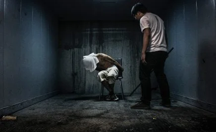 Staged photo of a man being tortured in a dark room
