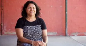 Glenda Joyce Kickett, a Noongar woman from Perth standing in front of a red wall