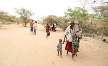 A man walks with a young boy carrying their possessions in Dadaab Refugee camp - Kenya