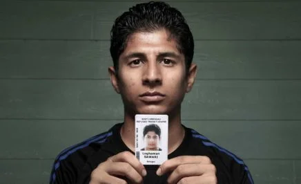 Refugee Loghaman Sawari holding an ID card