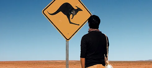 man stands infront of a kangaroo sign on a desert road