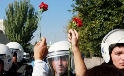 People hold carnations in front of riot police during clashes in Turkey