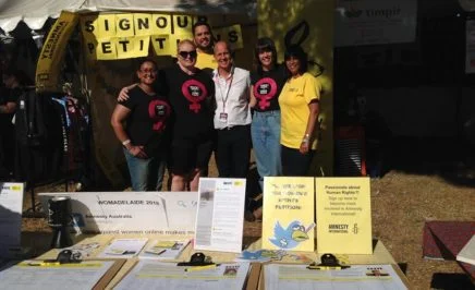 Amnesty's women's rights activists stand in front of a stall at WOMAD