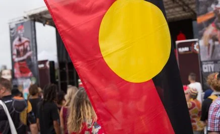 The Aboriginal Flag being flown at Yabun Festival 2018, in the distance is a stage and festival participants