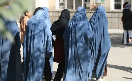 Afghan women dressed in blue with their backs to the camera on their way to vote.