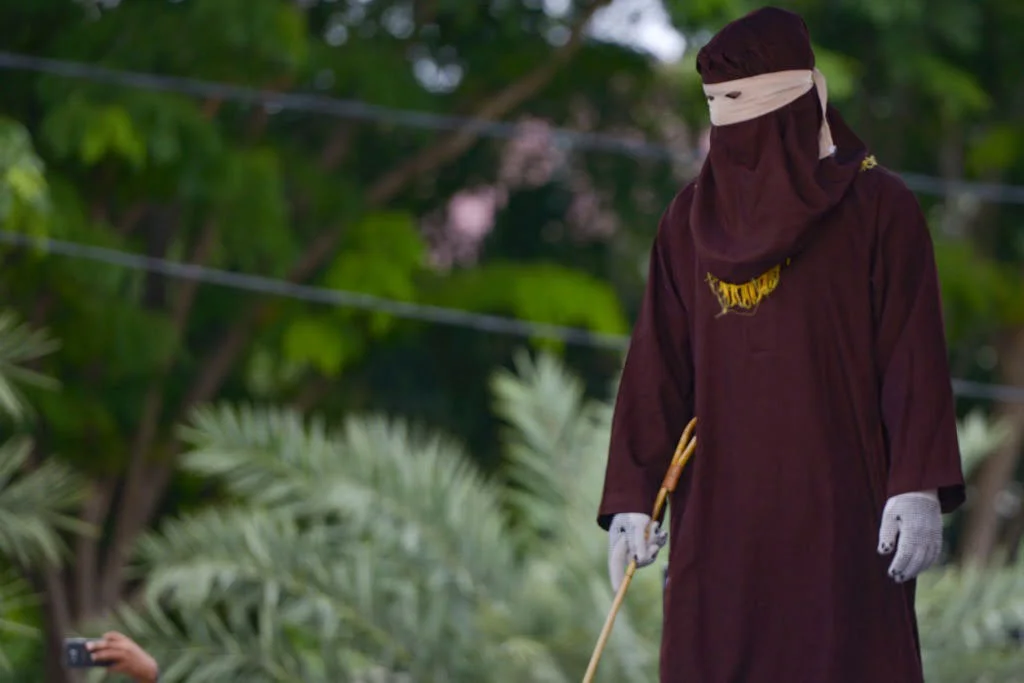 Sharia police waiting and holding a cane