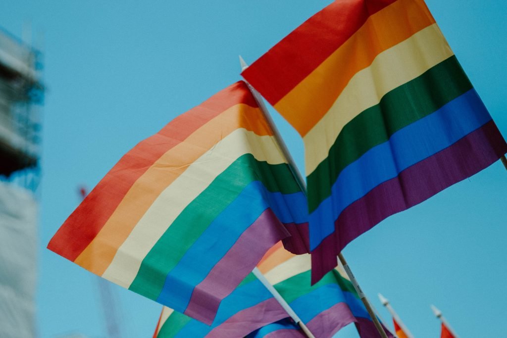 LGBTQIA+ flags waving against a blue sky